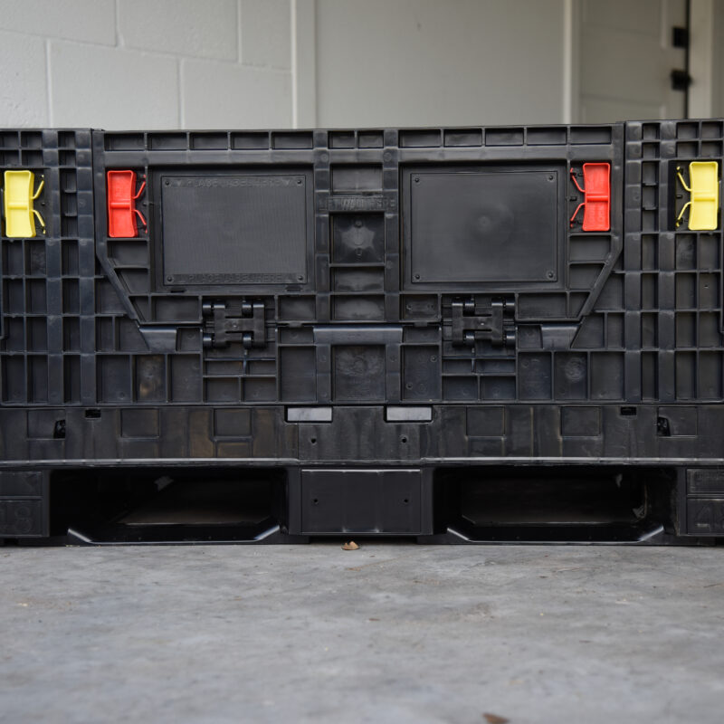 Front view of a Monoflo BC 4844.5-25 collapsible bulk container with yellow and red handles