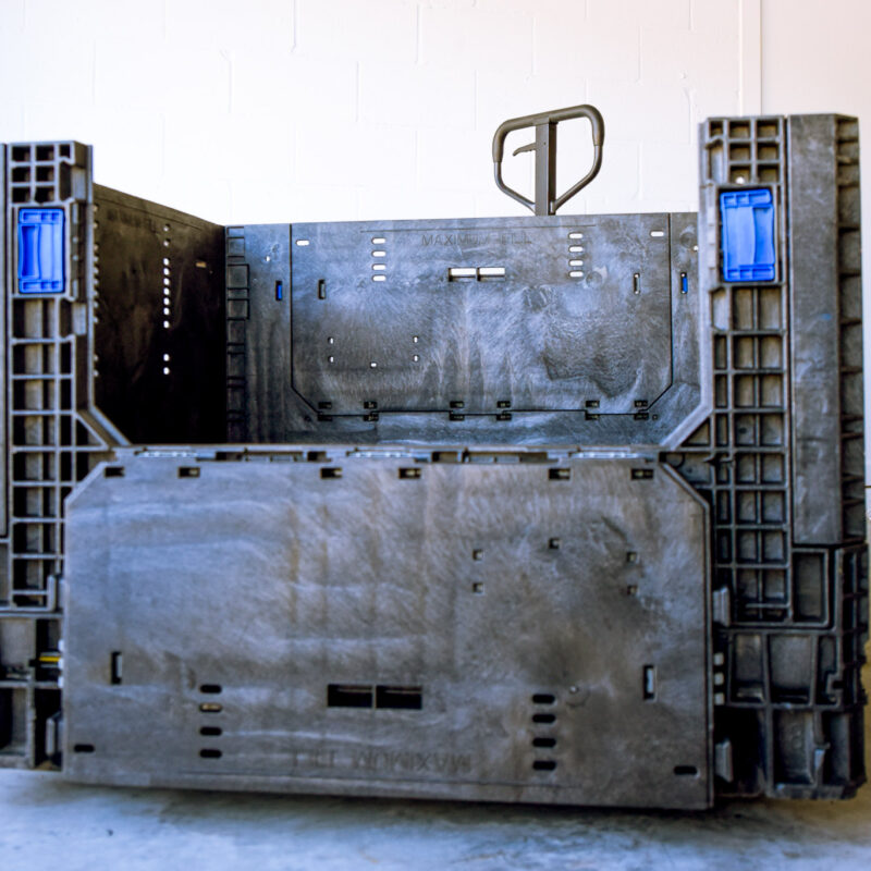 Used black collapsible bulk container with the front access door lowered and blue latches.